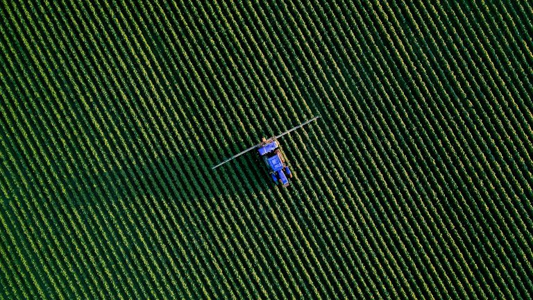 Pulverizador agrícola em lavoura representando calibração, dose por hectare e volume de calda do AGRONEEM