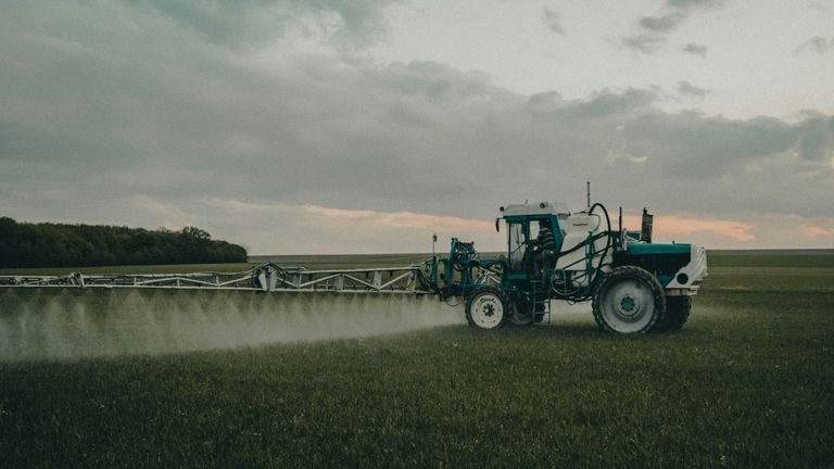 Trator com pulverizador em campo representando tecnologia de aplicação foliar