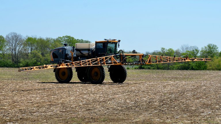 Pulverizador agrícola em campo representando ajuste de volume de calda do ONMETA